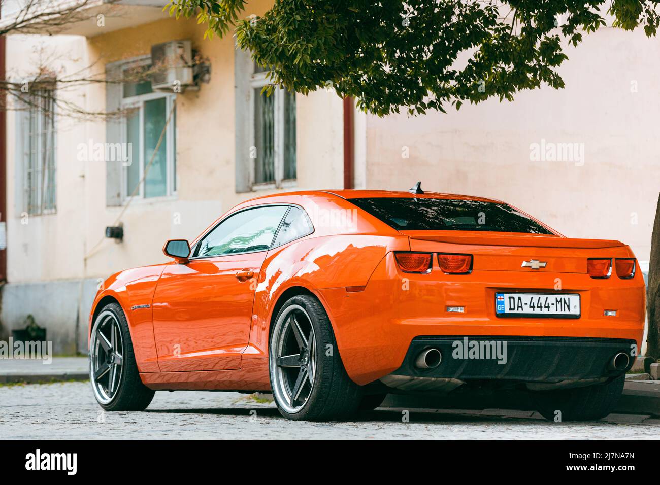 Voiture Orange Chevrolet Camaro garée dans la rue. Sixième génération Banque D'Images