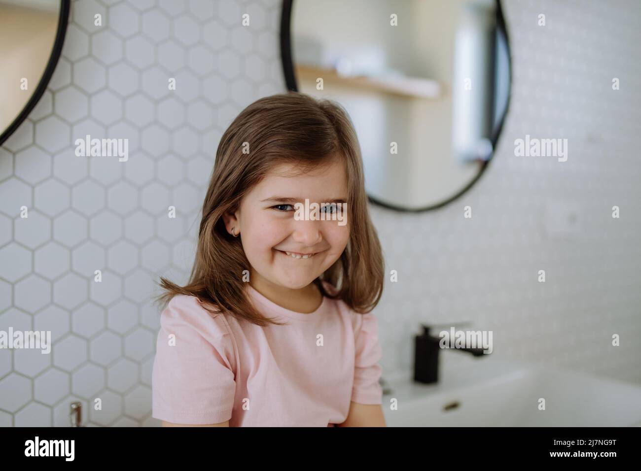 Portrait d'une petite fille heureuse dans la salle de bains, regardant l'appareil photo. Banque D'Images