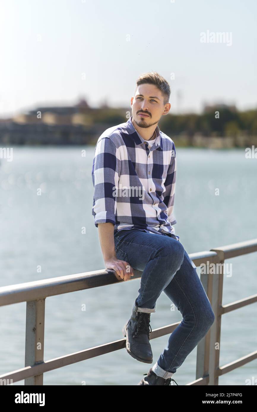 jeune homme gay caucasien assis sur une jetée flottante Banque D'Images