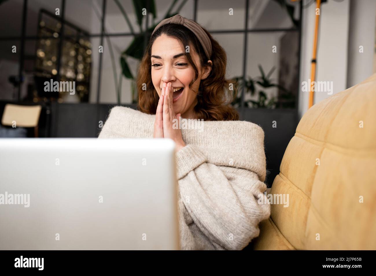 Femme excitée regardant l'écran d'ordinateur portable assis sur un canapé confortable à la maison Banque D'Images