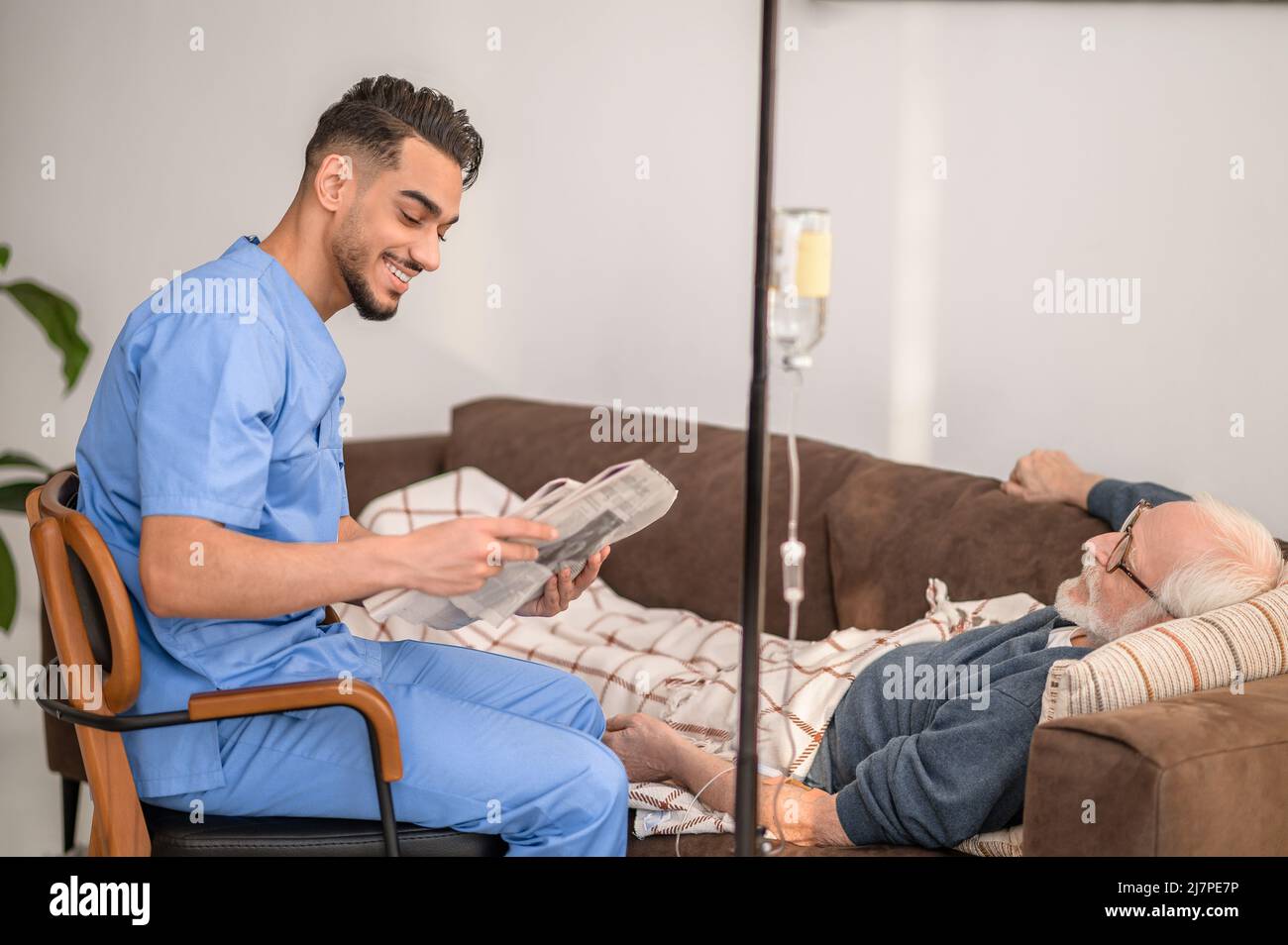 Infirmière à domicile qui divertit un patient sur la perfusion IV Banque D'Images