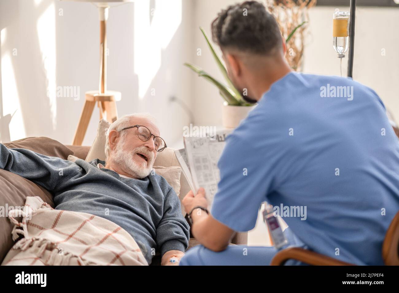 Soignant divertissant homme patient pendant le traitement par voie intraveineuse Banque D'Images