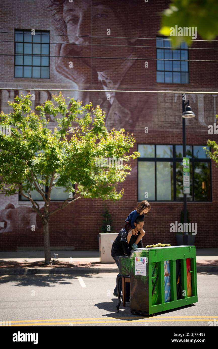 Tulsa, États-Unis. 06th mai 2022. Un père joue l'un des plusieurs pianos à l'extérieur du centre Bob Dylan, qui présente une fresque basée sur une photographie de Jerry Schatzberg en 1965, à Tulsa, Oklahoma, le vendredi 6 mai, 2022. Les pianos ont été un élément de Mayfest, le festival annuel des arts de Tulsa. (Photo de Jeff Wheeler/Minneapolis Star Tribune/TNS/Sipa USA) crédit: SIPA USA/Alay Live News Banque D'Images