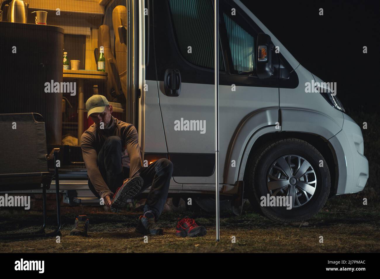 Des chaussures de randonnée qui changent devant sa camionnette de camping. Préparation de la piste tôt le matin. Catégorie de véhicule récréatif B. Banque D'Images