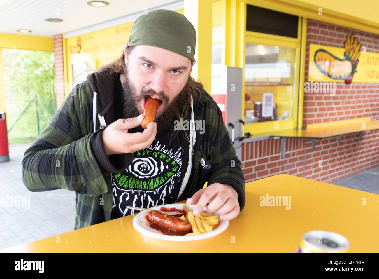 Un homme affamé raguait des currywurst et des frites frais dans un snack-bar en bord de route « Wurst and Frite's. Banque D'Images