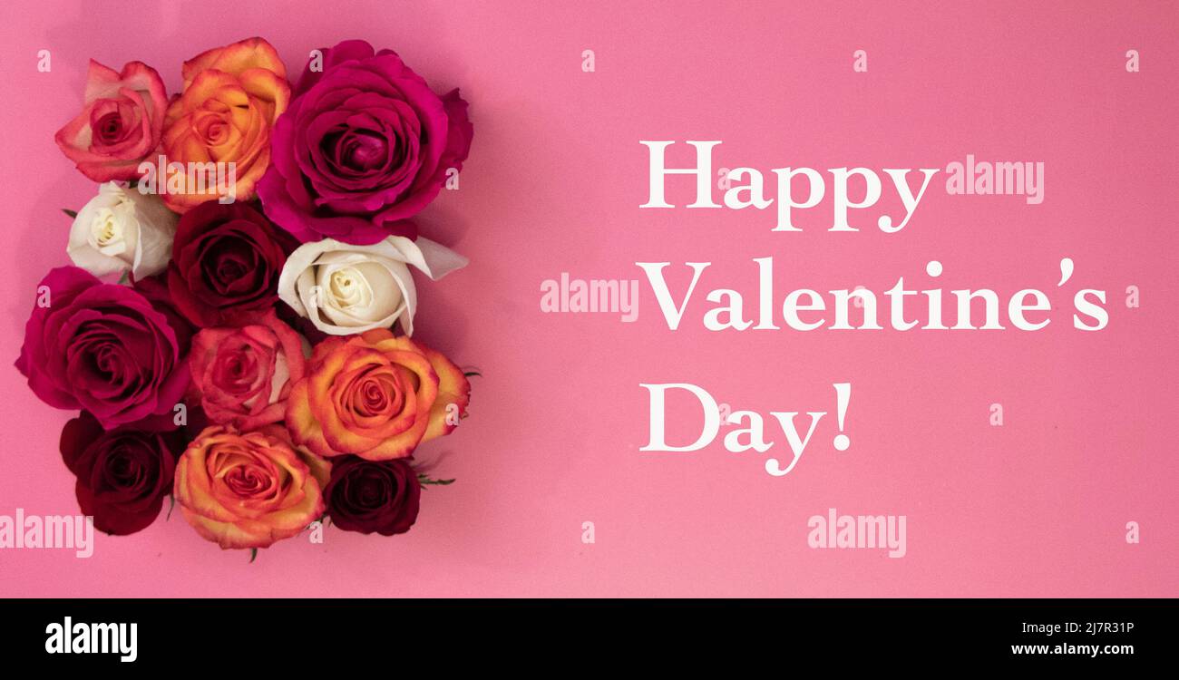 Bouquet de fleurs roses sur fond rose et texte de la Saint-Valentin en blanc. Banque D'Images