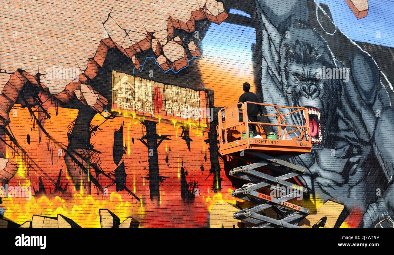 Un artiste peint un graffiti de King Kong sur l'ancienne usine de brique ( Joy Art bâtiment ) dans la zone d'art 798 à Beijing, Chine. Banque D'Images