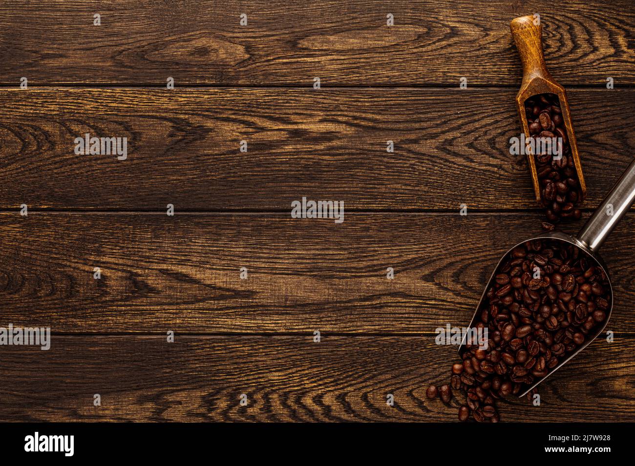 Grains de café dans la pelle sur fond de bois. Texture bois avec grains torréfiés dans une vieille spatule cuillère vue du dessus. Affiche publicitaire Banque D'Images