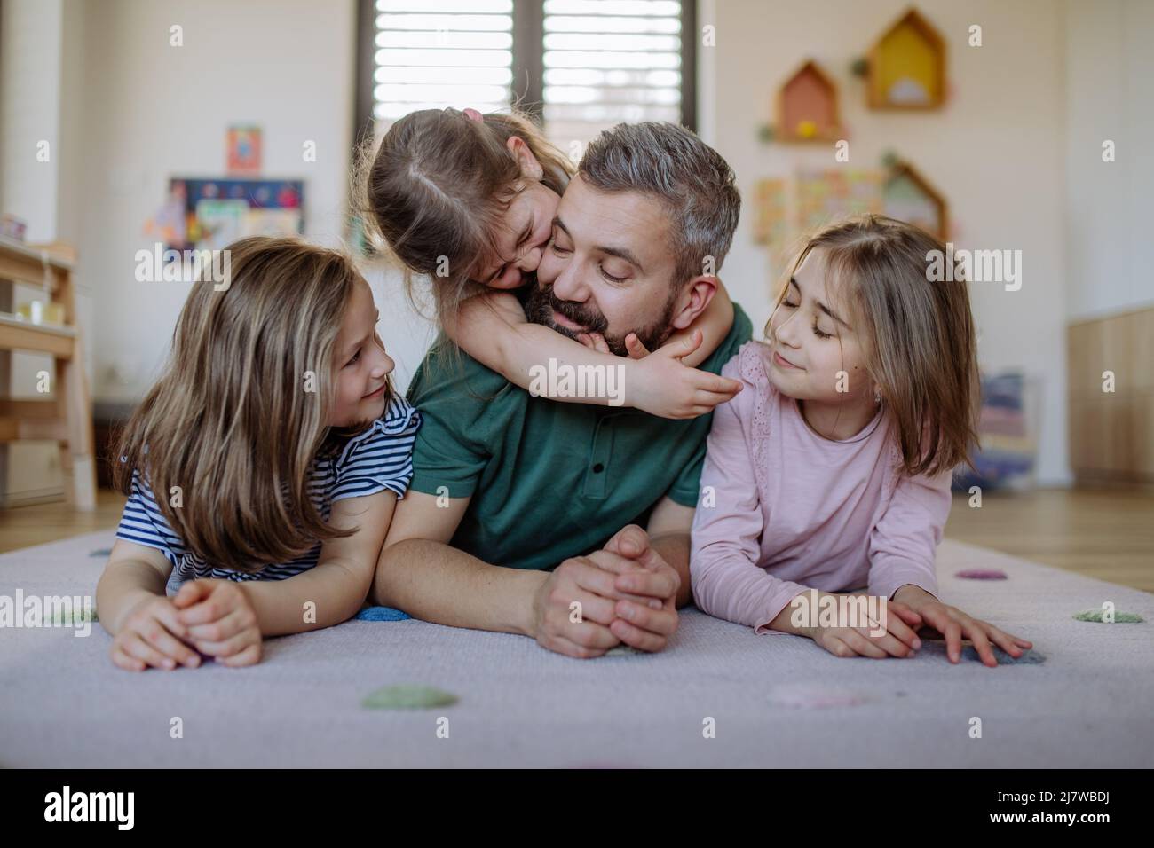 Père joyeux avec trois petites filles jouant ensemble à la maison. Banque D'Images