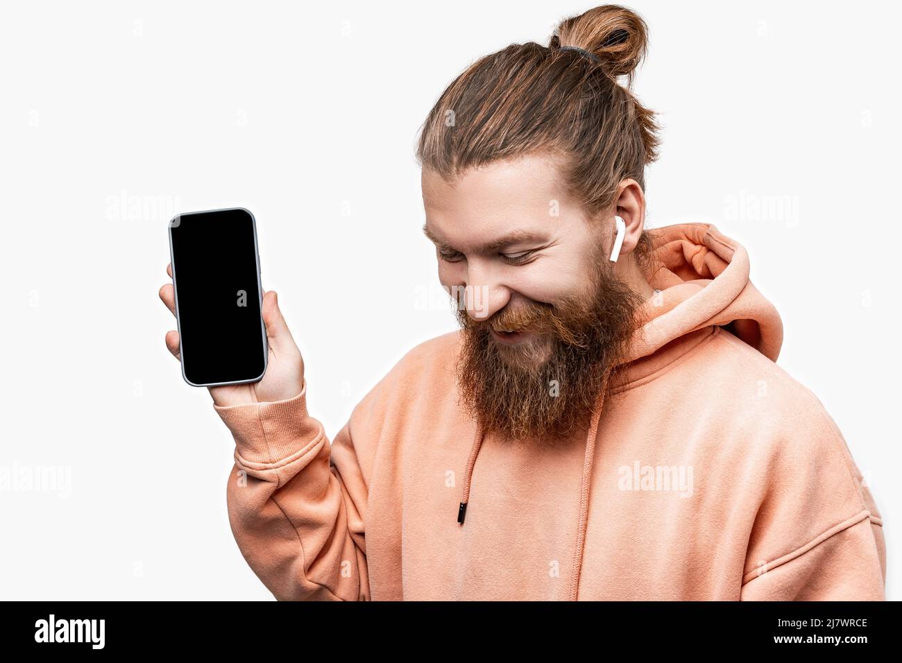 Homme de bonne humeur scandinave tenant un téléphone avec écran noir et casque sans fil isolé sur fond gris. Gars avec gingembre coiffé Banque D'Images