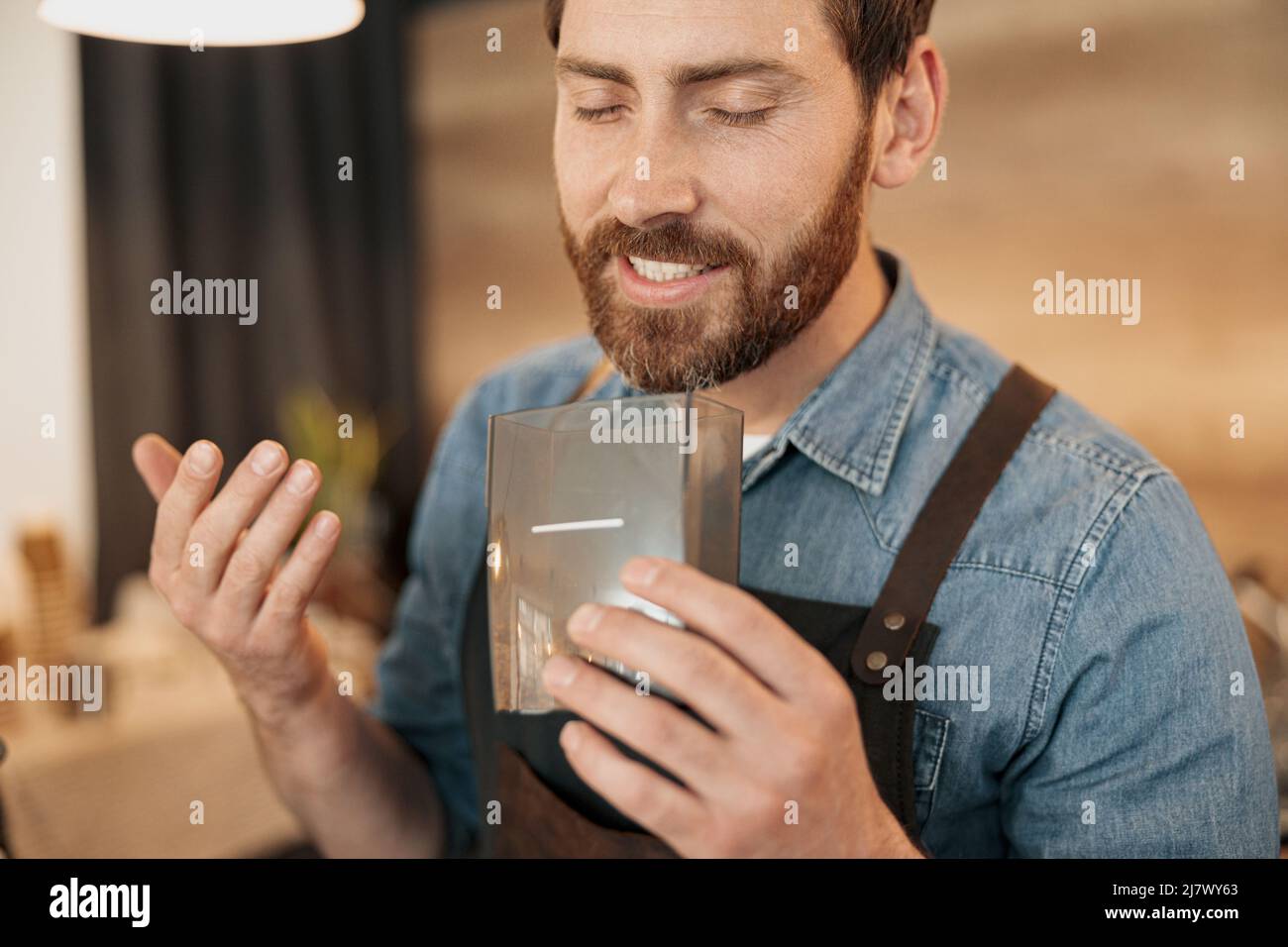 Le barista souriant apprécie l'arôme des grains de café Banque D'Images