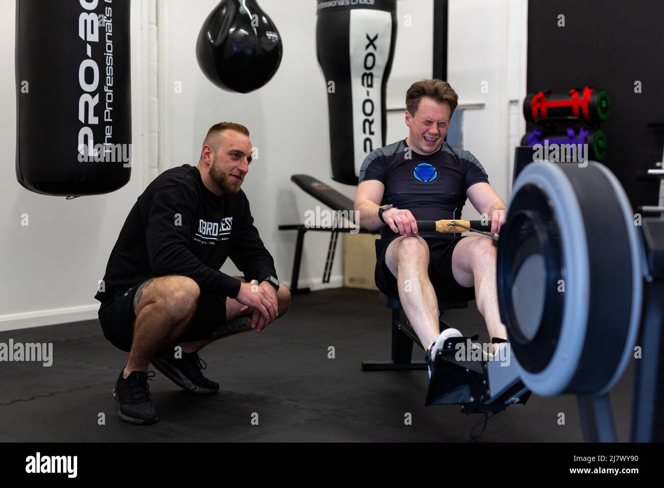 Ipswich Suffolk UK avril 03 2022: Un jeune homme en forme et en bonne santé ayant une session une à une avec un entraîneur personnel sur une machine à ramer Banque D'Images