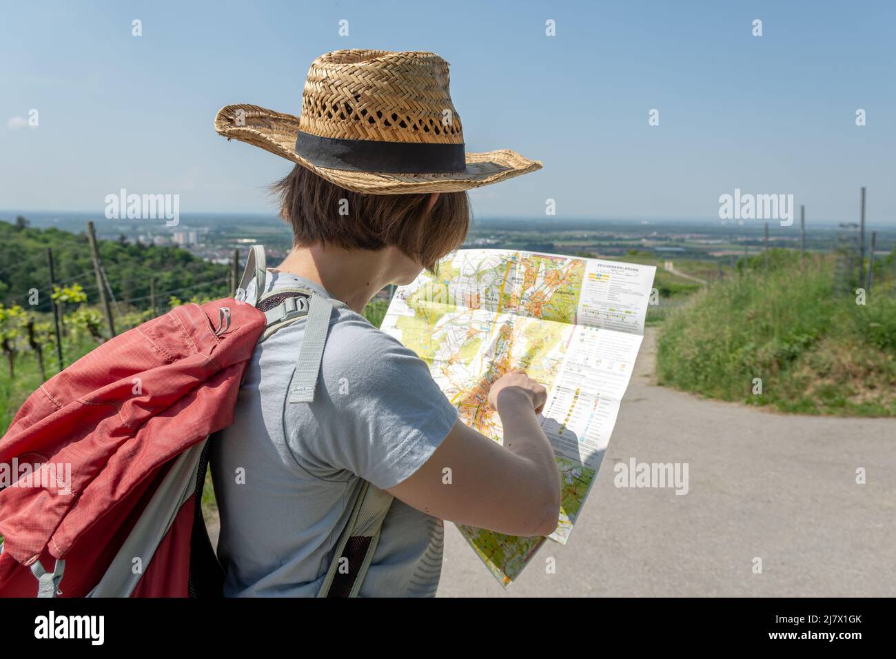 Femme de randonnée avec cheveux bruns, t-shirt gris, jeans, chapeau de  paille et sac à dos rouge debout à un carrefour de pays, regardant une  carte de randonnée Photo Stock - Alamy