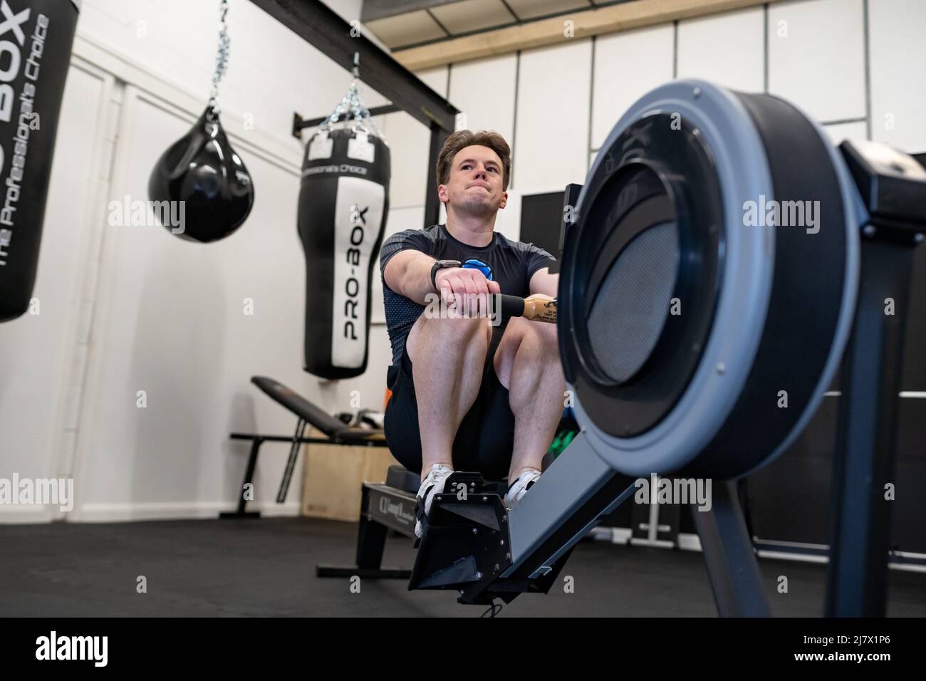Ipswich Suffolk UK avril 03 2022: Un jeune homme en forme qui s'efforce d'obtenir un rameur dans une petite salle de gym moderne Banque D'Images