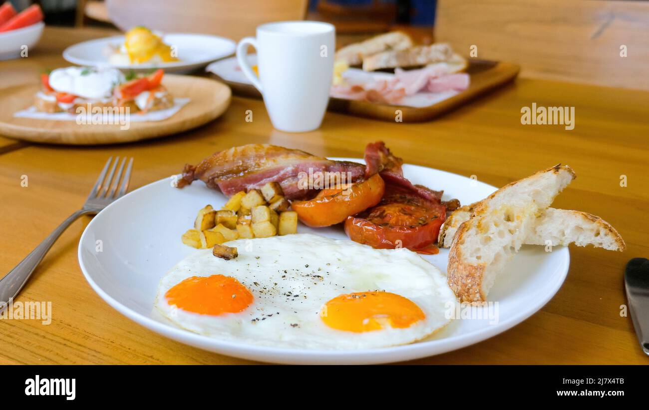 Petit-déjeuner américain avec œufs frais, bacon, tomates et pain grillé Banque D'Images