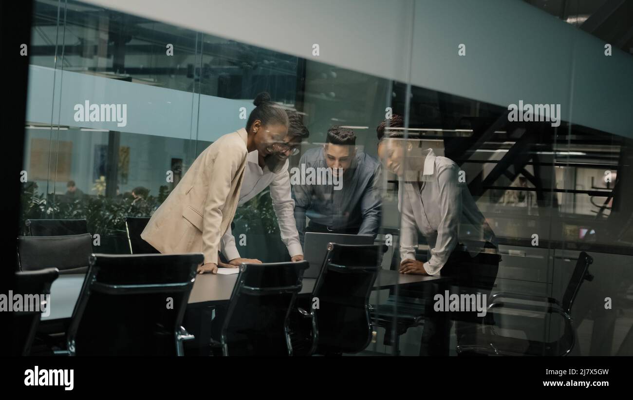 Collaborateurs d'une équipe professionnelle multi-ethnique regardant un ordinateur portable célébrant le succès d'un collègue oui Gesture gagnant entreprise collègues féliciter Banque D'Images