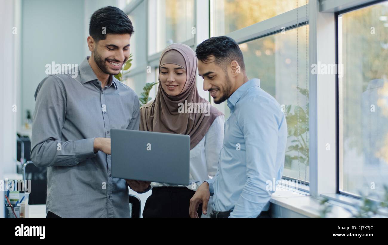 Des collègues multiethniques écoutent le chef d'équipe arabe expliquer l'application des tâches de l'entreprise à divers travailleurs indiens hommes d'affaires regardant sur l'écran d'ordinateur portable Banque D'Images