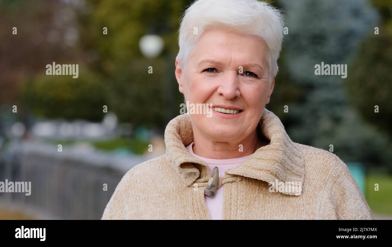 Portrait en gros plan heureuse belle femme bienveillante en âge de retraite. Calme souriant femme mûre dans des vêtements décontractés avec cheveux courts gris élégant Banque D'Images
