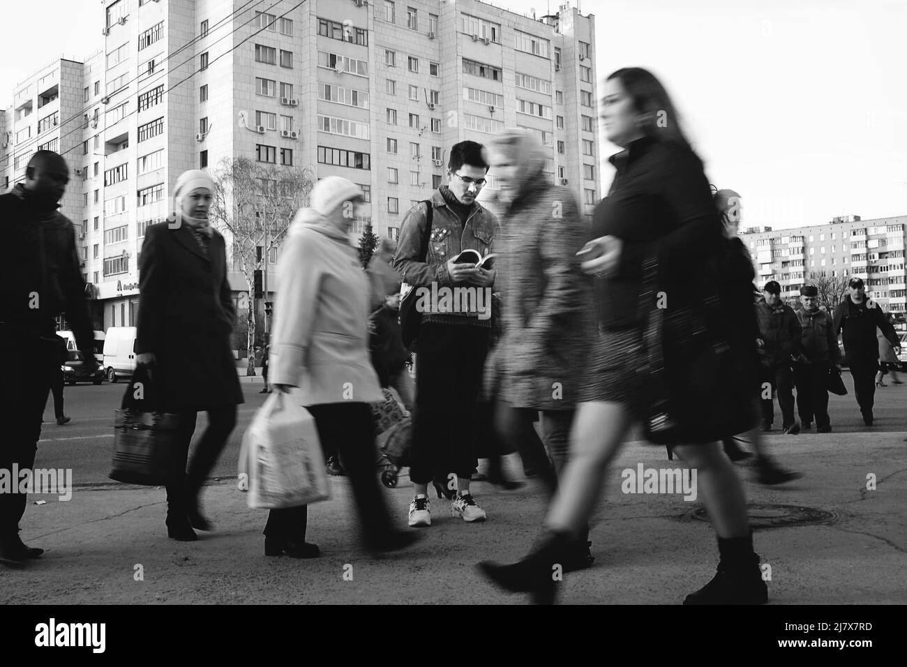 La Russie, Tioumen, 19.04.2017. Un jeune homme tenant un livre ouvert, les gens qui marchent autour de lui. Guy élégant de couvaison de lire un livre sur une rue bondée. Blac Banque D'Images