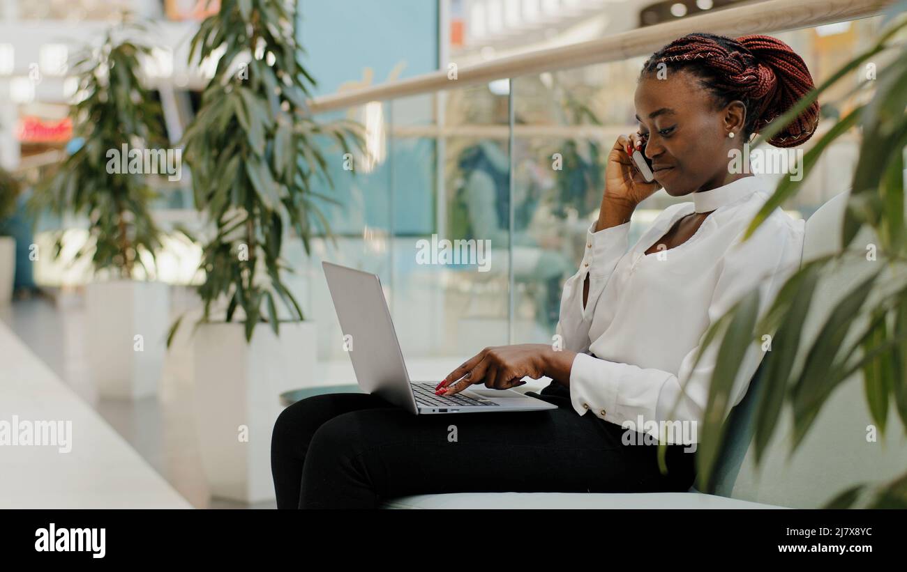 Jeune fille freelancer entreprise femme chef de patron femelle assis sur un canapé dans la société de bureau parlant téléphone négociations dactylographiant sur ordinateur portable fonctionne en ligne Banque D'Images