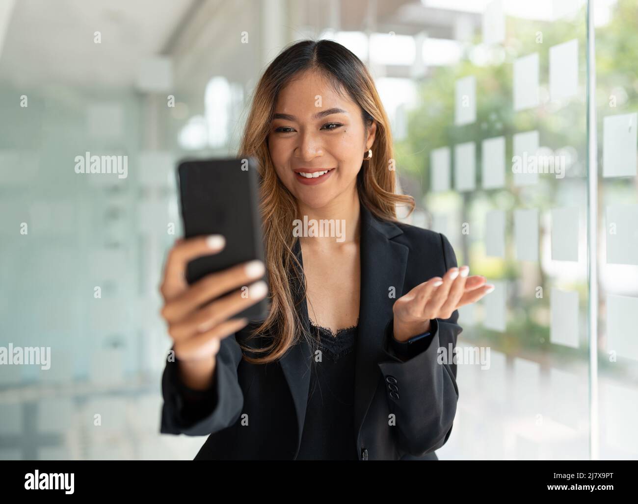 Femme d'affaires asiatique agitant les poings, a obtenu de bonnes nouvelles sur le téléphone mobile intelligent dans le bureau, le réseau social, les appels vidéo, la communication. Banque D'Images