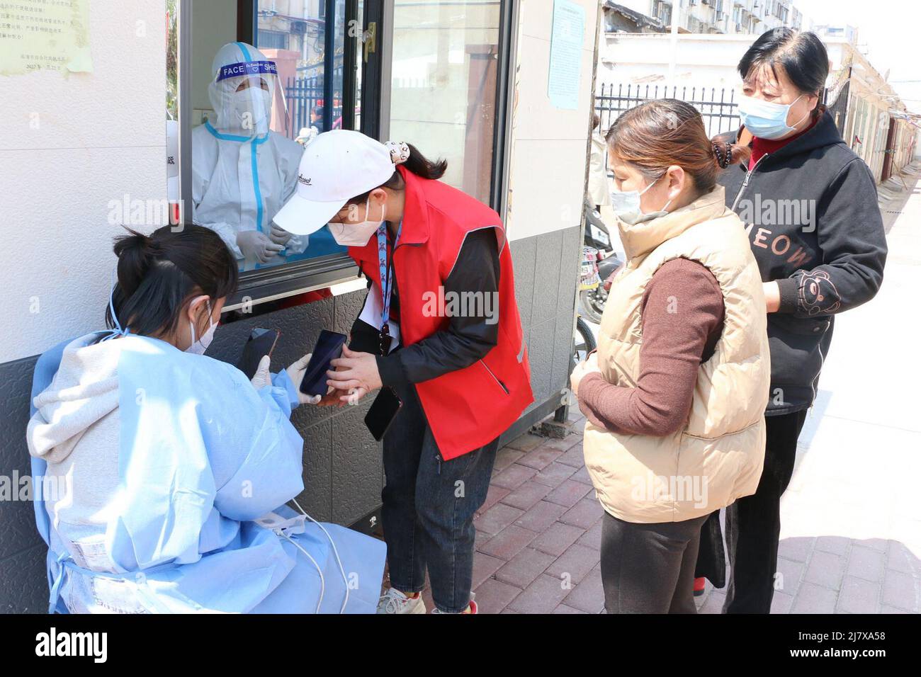 Jinan. 11th mai 2022. La photo prise le 19 avril 2022 montre Wang Junru (1st L) aidant les gens à enregistrer des informations sur un site de test des acides nucléiques à Linqing, dans la province de Shandong, dans l'est de la Chine. POUR ALLER AVEC 'China Focus: La Chine étend les emplois de bien-être public pour les groupes vulnérables en faveur de la prospérité commune' crédit: Xinhua/Alay Live News Banque D'Images