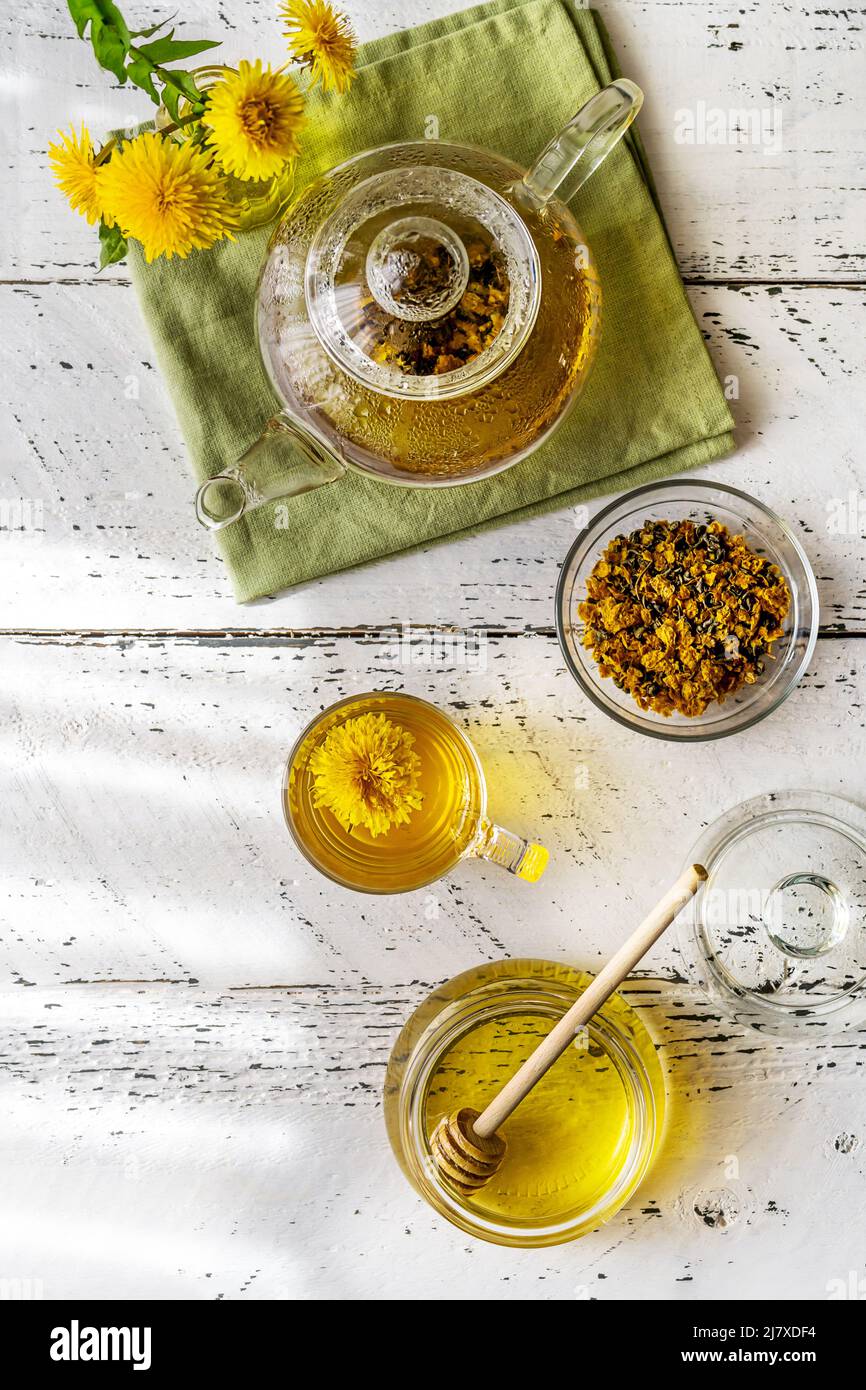 Thé pissenlit et miel sur la table en bois blanc avec théière, fleurs pissenlit, mélange sec pour le thé. Pose à plat Banque D'Images