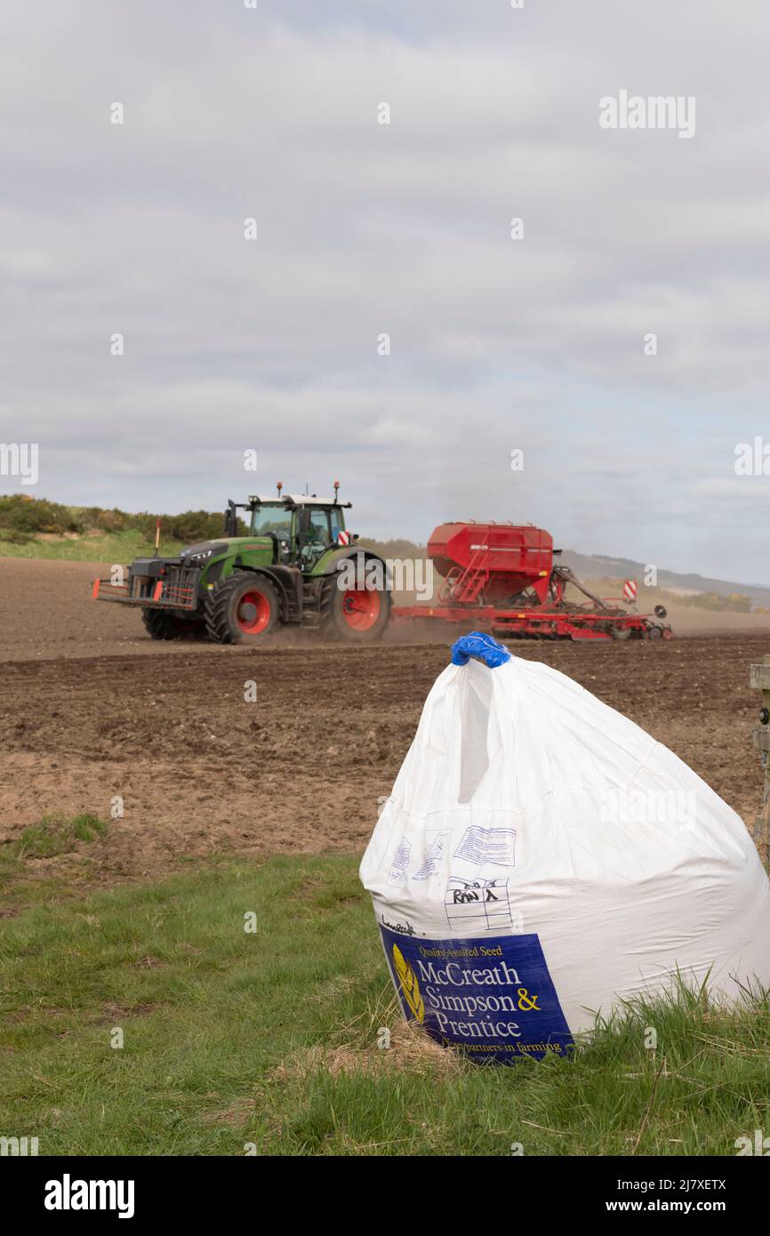 Un tracteur Fendt et un semoir Horsch fonctionnant dans un champ labouré à Aberdeenshire, avec un sac de semences du commerçant assis à l'entrée du champ Banque D'Images