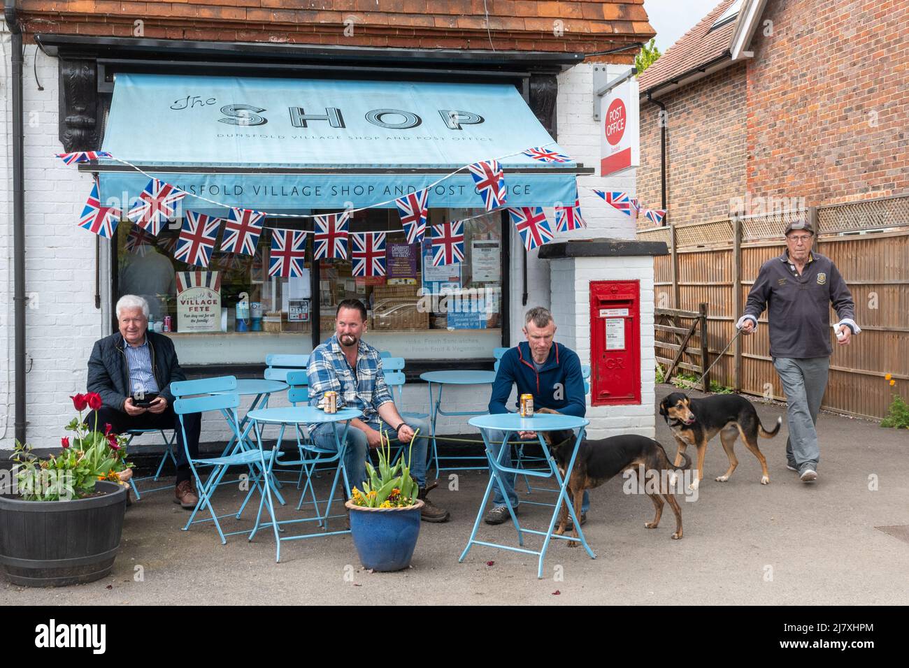 Dunsfold Village Shop, Surrey, Angleterre, Royaume-Uni, le jour de la fête annuelle avec des hommes assis dehors prenant des boissons Banque D'Images
