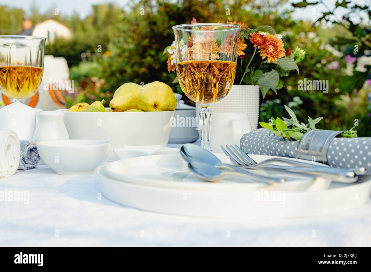 Mise en place de la table des fêtes d'été. Table élégante avec vaisselle blanche sur nappe blanche. Fruits mûrs, boissons dans des verres en cristal. Jeu de tables pour Banque D'Images
