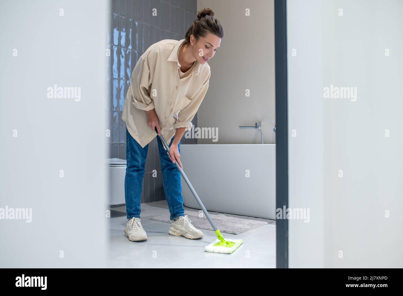 Une jeune femme nettoie le sol à la maison Banque D'Images