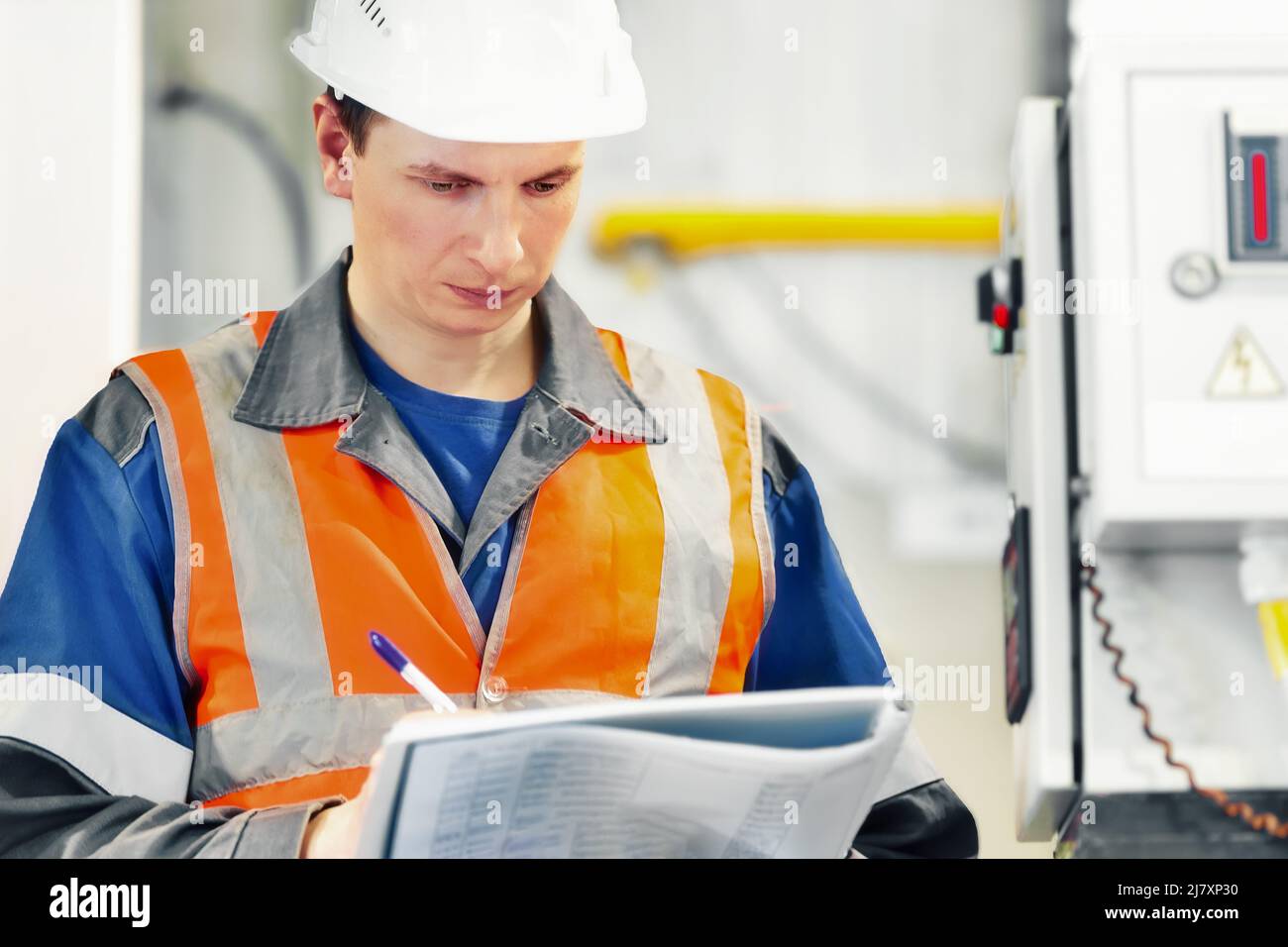 Le jeune ingénieur du casque et du gilet de protection enregistre les relevés des appareils ou de la consommation de gaz dans la chaufferie. Début de la saison de chauffage et approvisionnement en gaz. Banque D'Images