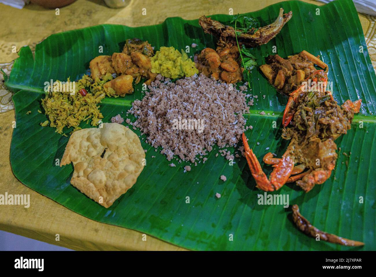 repas traditionnel de pittu de jaffna servi sur une feuille de banane entourée de cari de crabe de jaffna, de poisson local, de curry de crevettes, de pommes de terre de légumes et de papopadom Banque D'Images