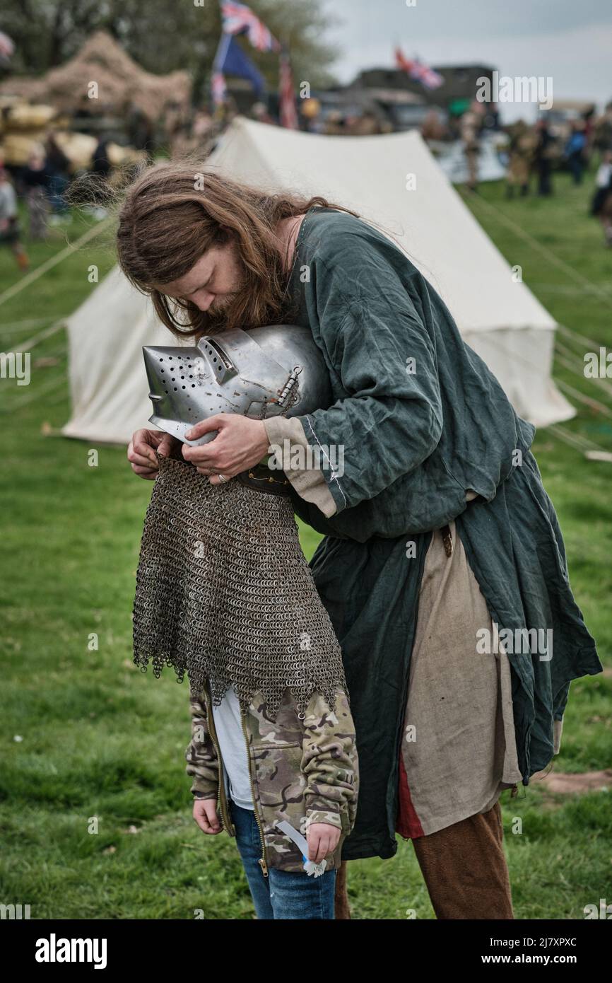 Un guerrier viking aide un garçon à retirer le casque d'un chevalier lors de l'événement No Man's Land au Bodrhyddan Hall, au pays de Galles Banque D'Images
