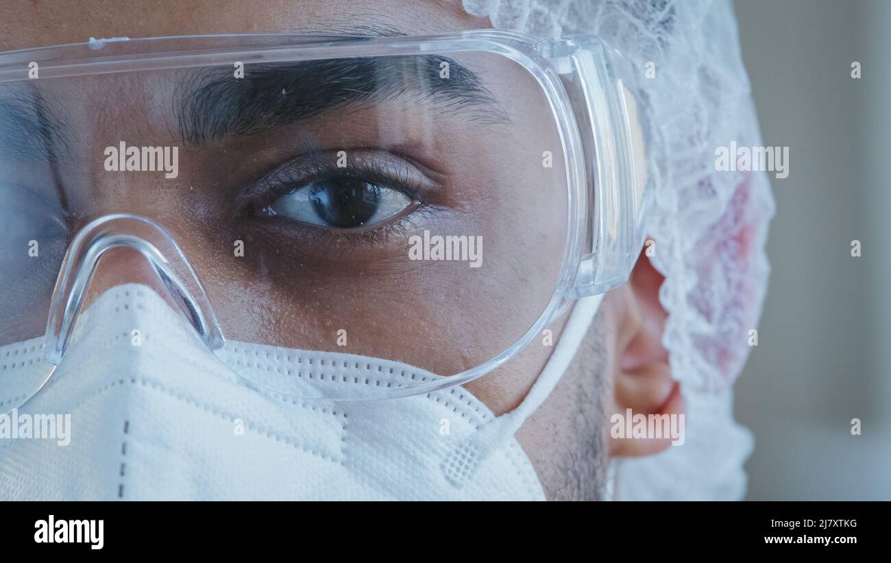 Gros plan homme noir fatigué et endormi œil moitié visage homme médecin portant des lunettes de protection personnel médical vêtements spéciaux uniforme travaillant à l'hôpital Banque D'Images