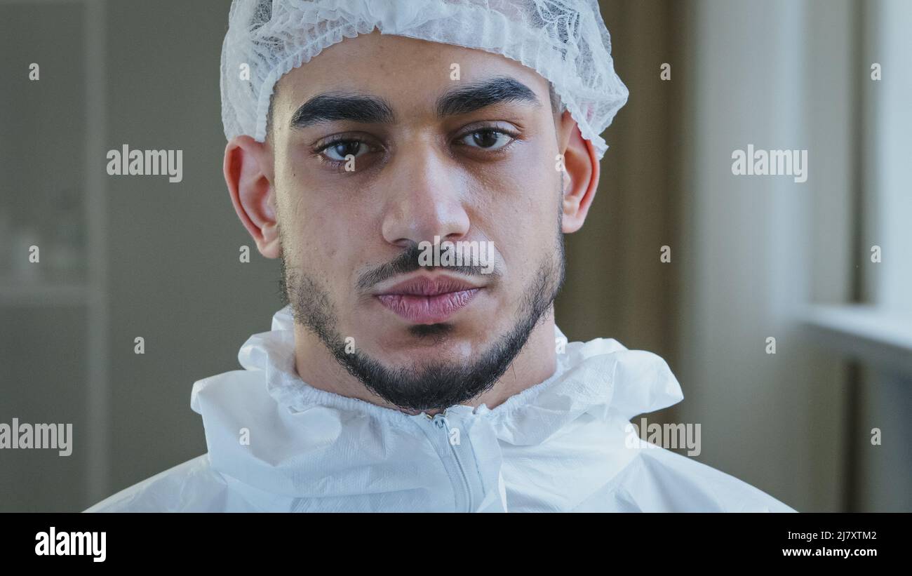 Portrait de jeune arabe fatigué épuisé médecin infirmier praticien dans l'uniforme de protection gants en latex tient dans la clinique prend la casquette médicale de Banque D'Images