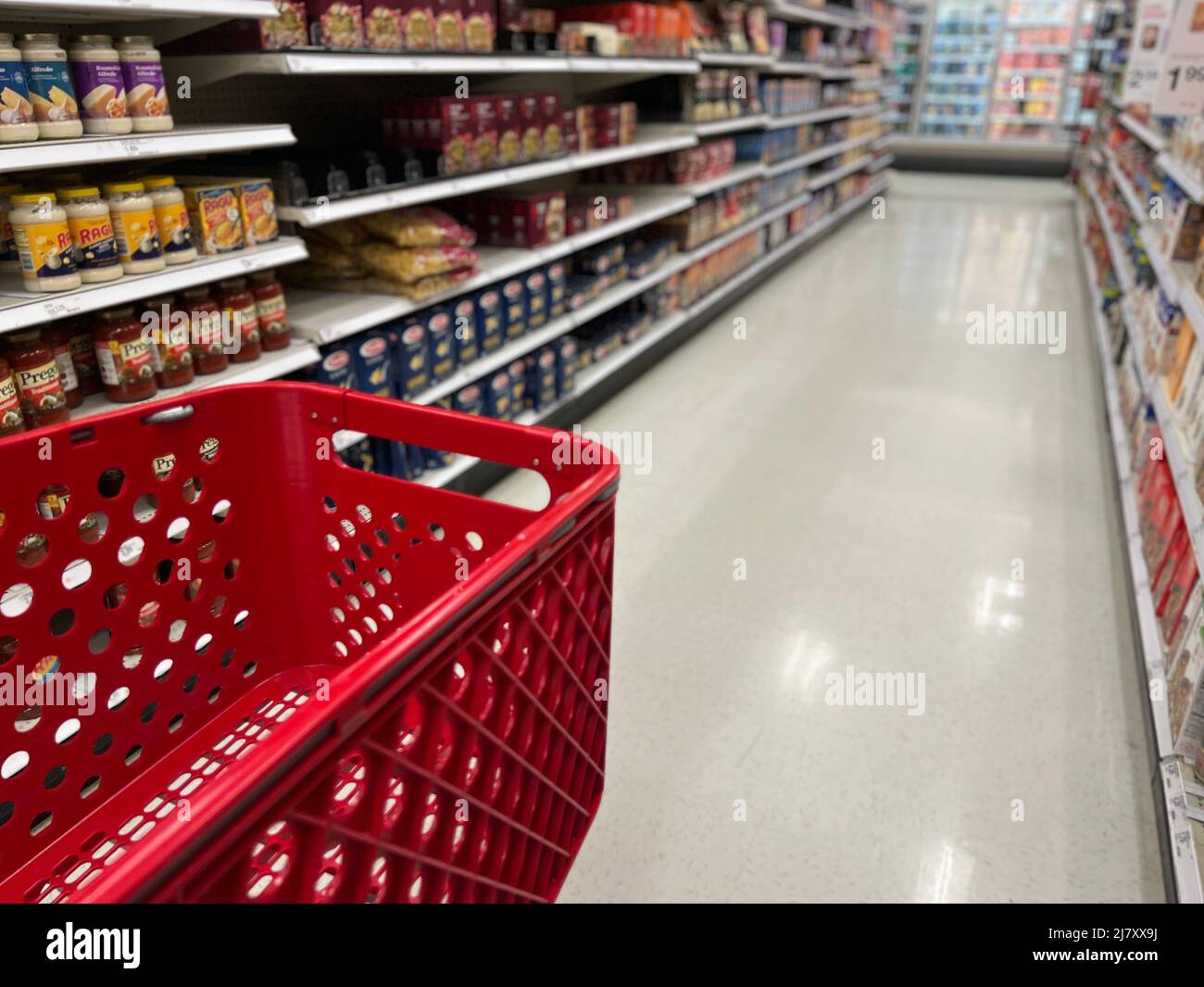 Chariot d'épicerie rouge dans les allées floues d'un magasin Target. Banque D'Images