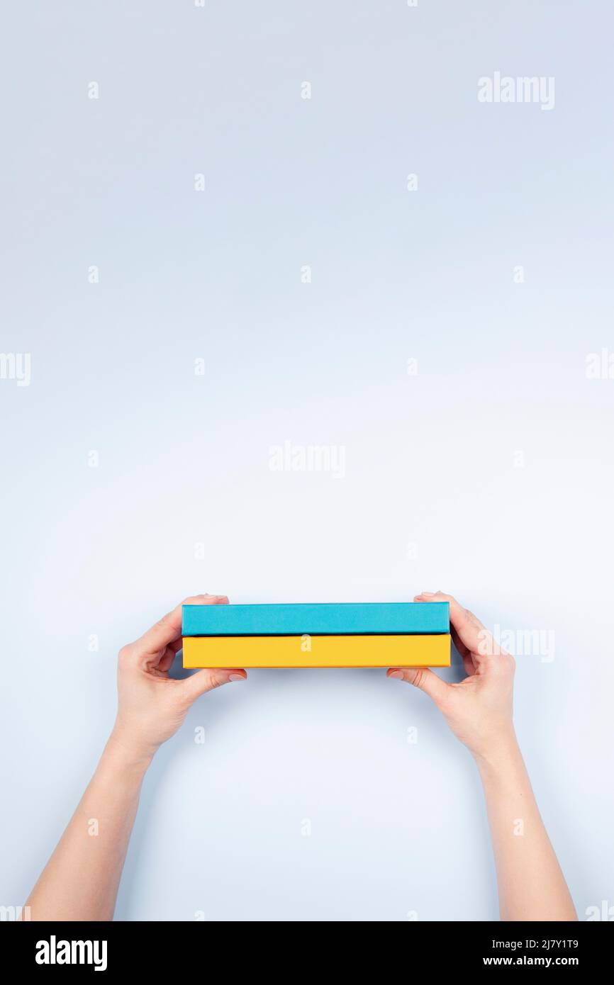 Femme mains tenant deux livres de couleur bleu et jaune sur fond bleu clair. Éducation, auto-apprentissage, échange de livres Banque D'Images