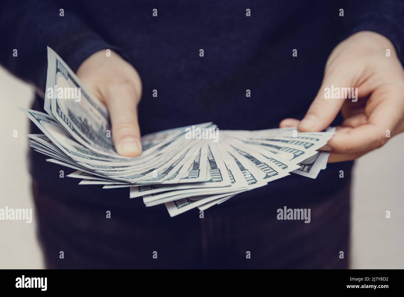Un homme tient un fan de 100 billets de dollars dans ses mains, foyer sélectif Banque D'Images