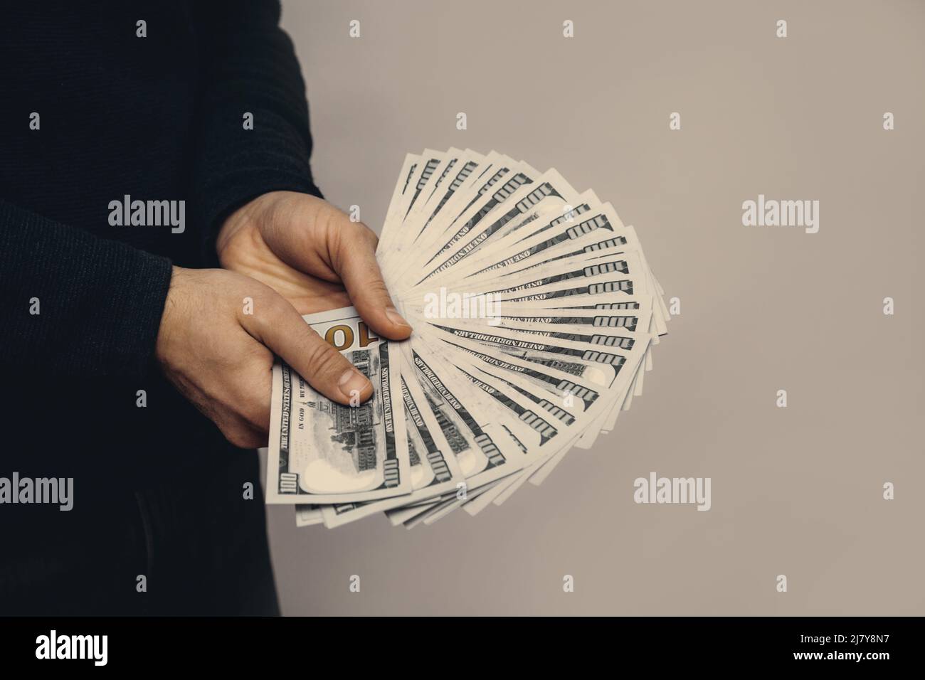 Un homme tient un fan de 100 billets de dollars dans ses mains. Banque D'Images