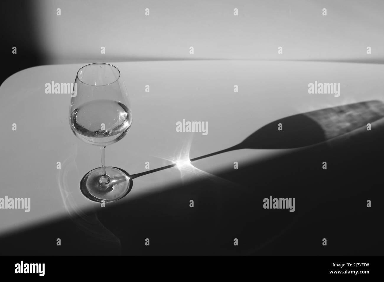 Un verre d'eau sur un fond blanc avec une ombre. Chiaroscuro de la fenêtre. Gros plan, espace de copie. Banque D'Images