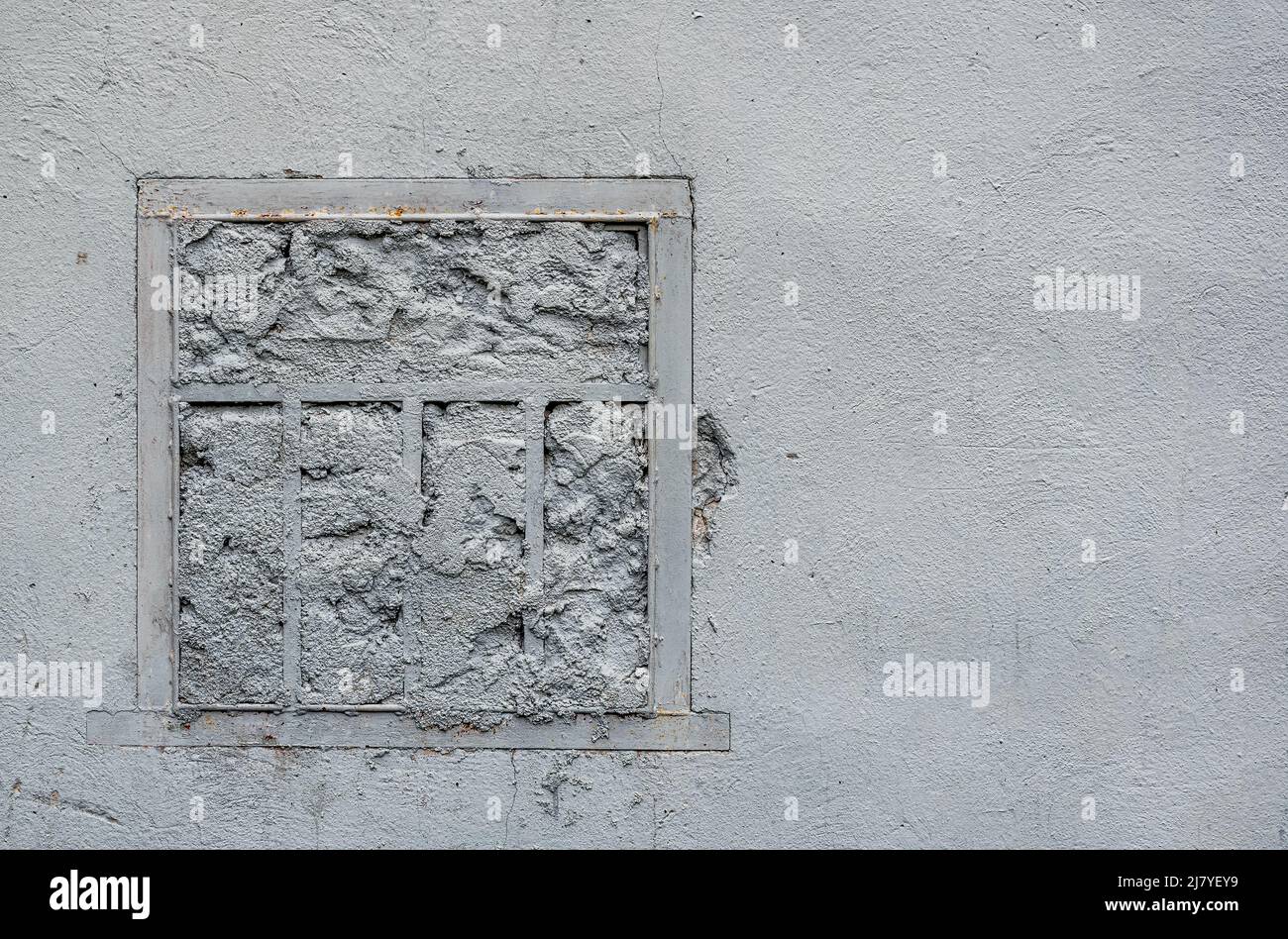 Fenêtre avec calandre, dans un ancien mur peint en blanc. Photo ou texture d'illustration Banque D'Images