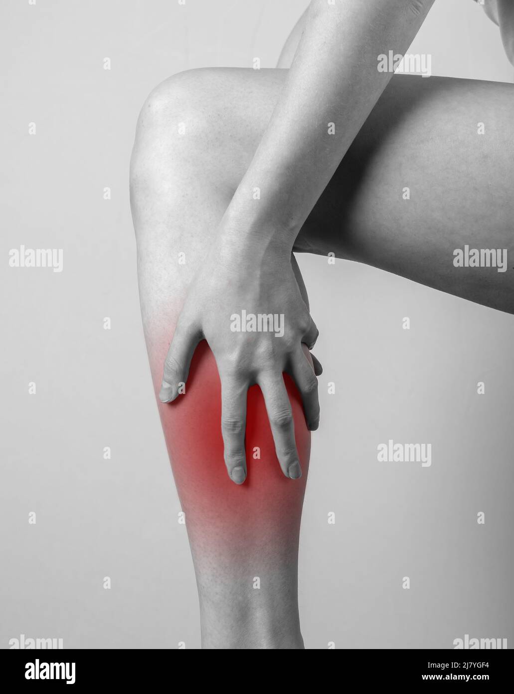 Douleur de shin. Femme tenant une jambe avec un point rouge. Tendons, inflammation des muscles, blessures, conséquences des ecchymoses osseuses. Noir et blanc. Photo de haute qualité Banque D'Images
