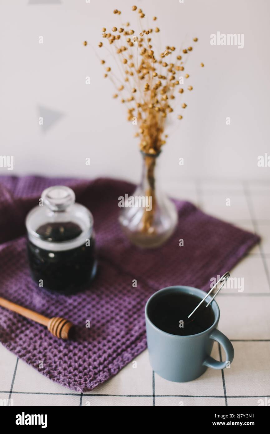 Thé noir sec dans un pot en verre et fuseau de miel sur fond de cuisine. Boisson chaude en période froide Banque D'Images