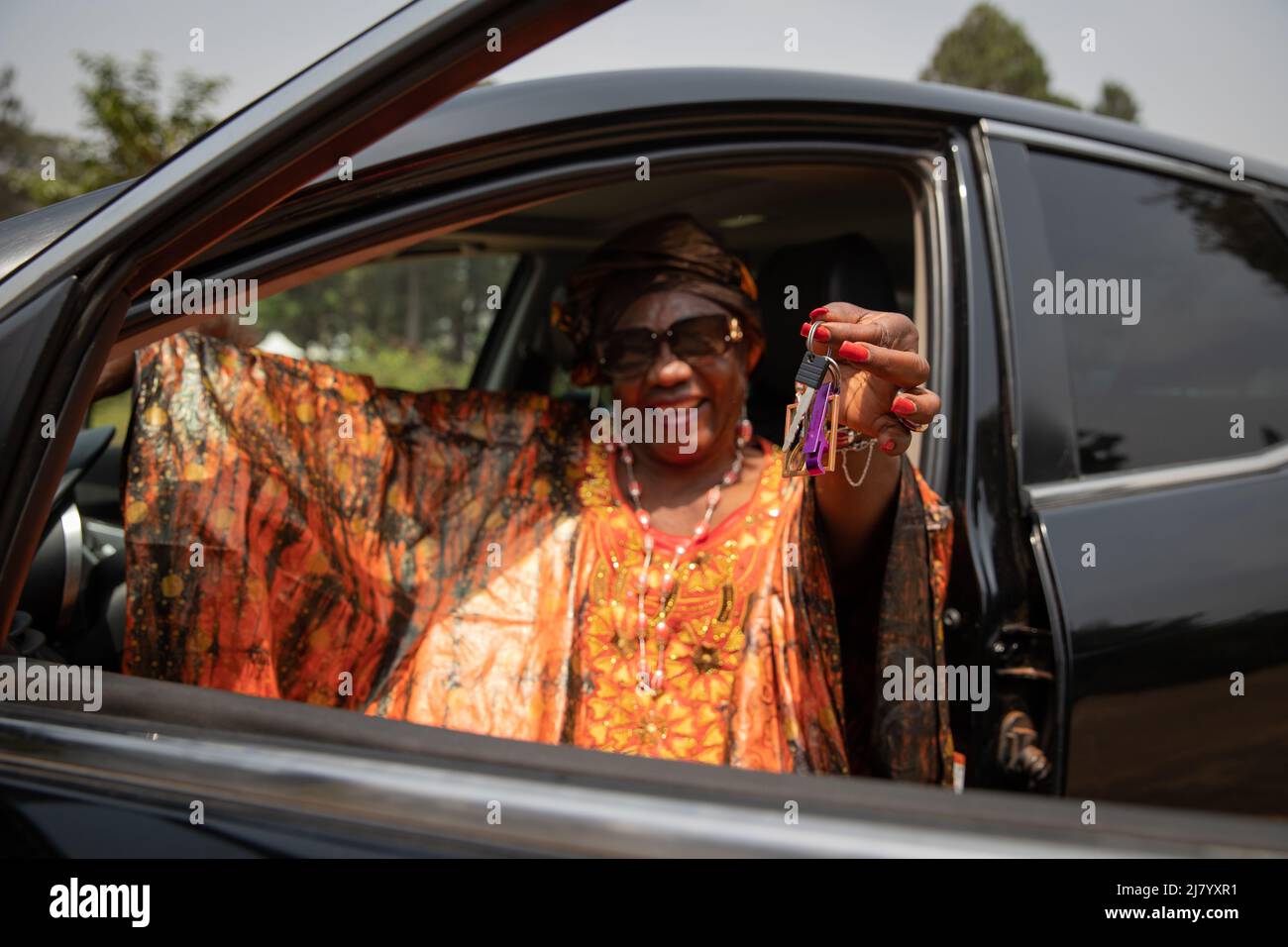 une dame africaine assise dans sa voiture tient les clés dans sa main, concept de services de location de voiture Banque D'Images une dame africaine assise dans sa voiture tient les clés dans sa main, concept de services de location de voiture Banque D'Images