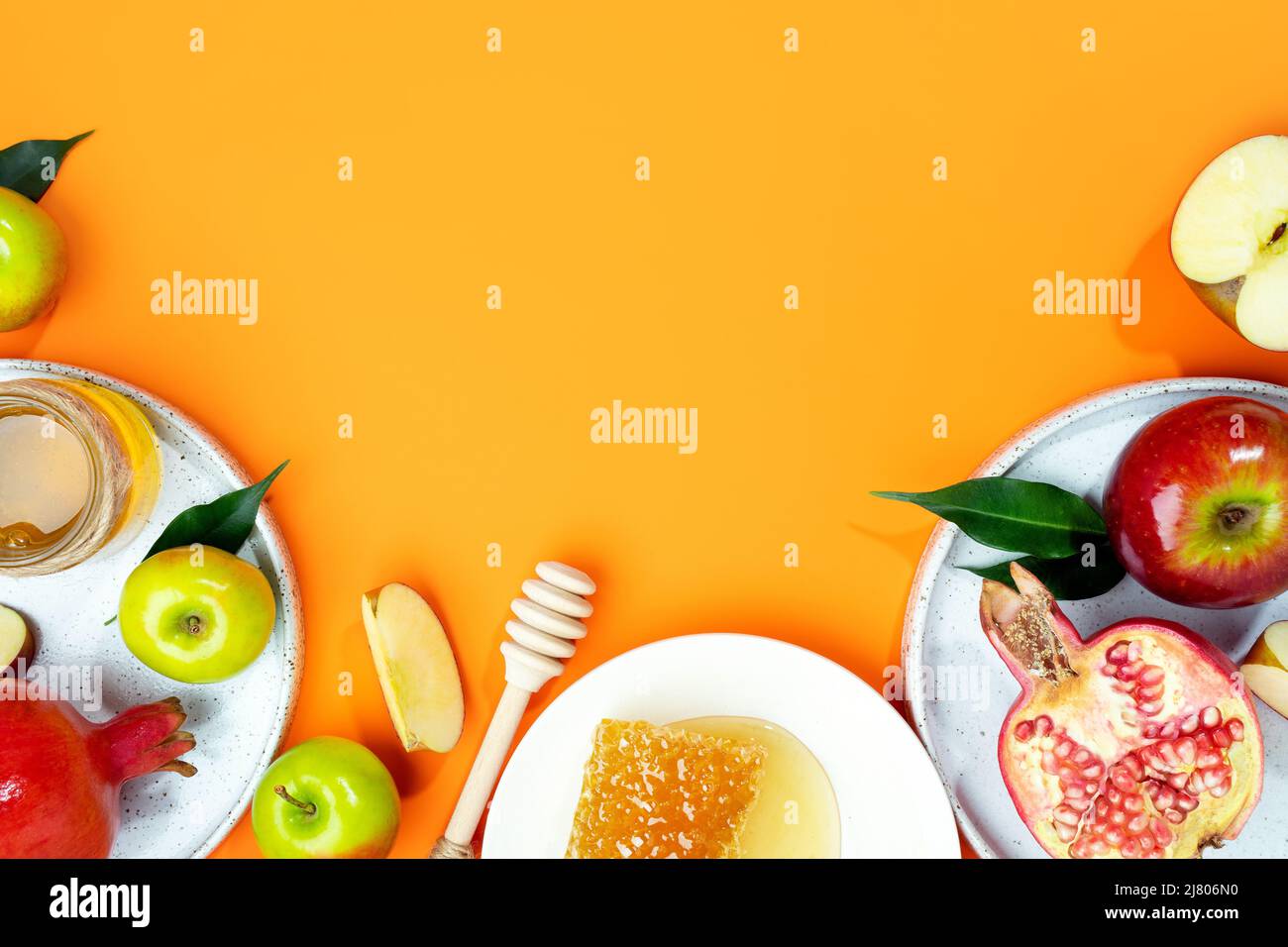 Miel, pomme et grenade sur fond orange. Concept juif nouvel an Joyeux vacances Rosh Hashanah. Mise en page créative des symboles traditionnels. Vue Banque D'Images