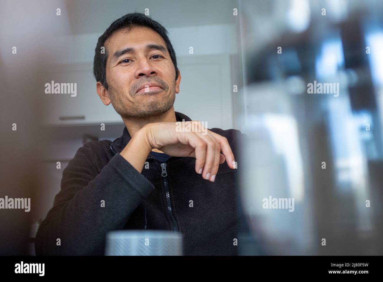 Homme souriant assis à une table de cuisine Banque D'Images