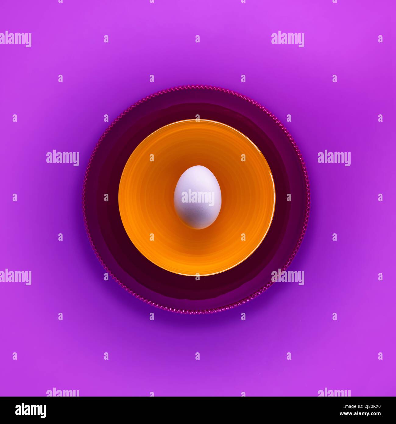 Vue de dessus d'un œuf dans un bol sur fond violet Banque D'Images