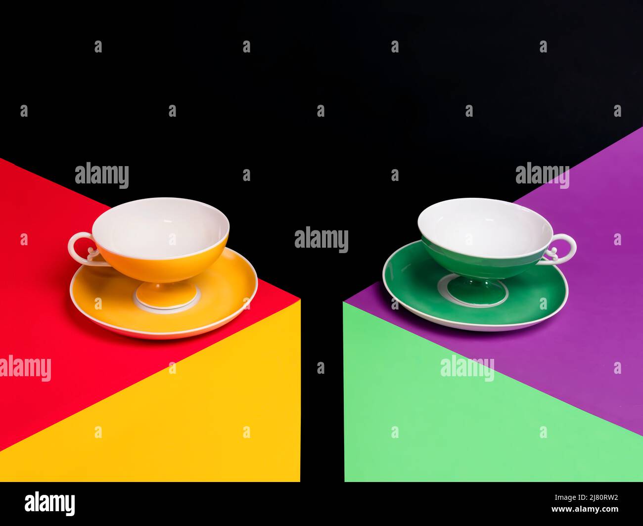 Deux tasses de thé vides colorées qui se levent des soucoupes sur deux tables multicolores Banque D'Images