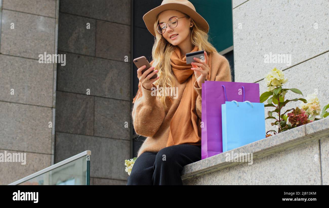 Millénaires fille faire des achats en ligne en utilisant le téléphone et la carte de crédit nods tête positive femme custimer joyeusement dansant la femme caucasienne souriant Banque D'Images